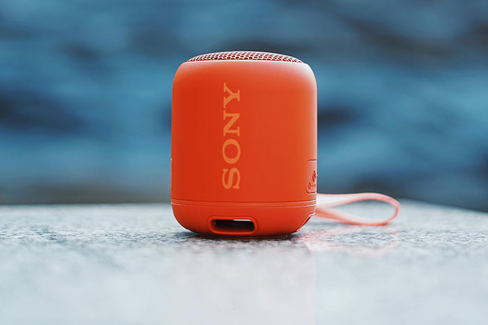 Orange Sony portable speaker placed on a reflective surface, illustrating some of the worst gifts people have received.