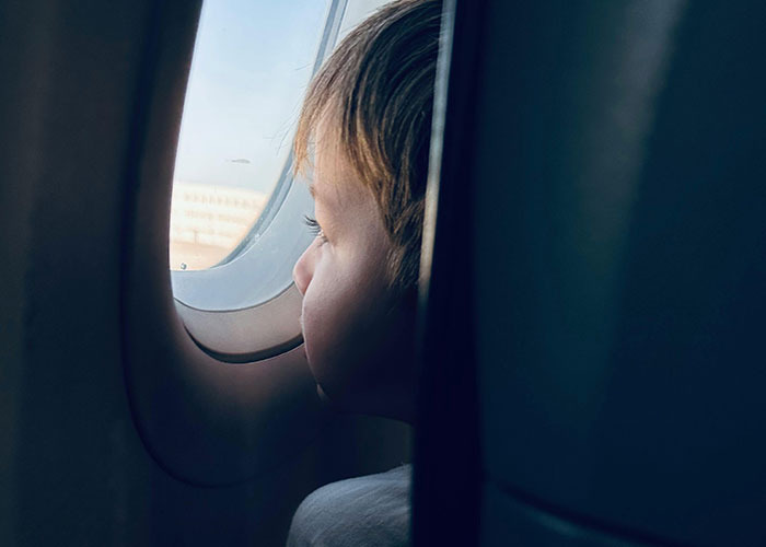 Child looking out airplane window, capturing a moment of entitlement among 50 people likely to win awards in 2025.