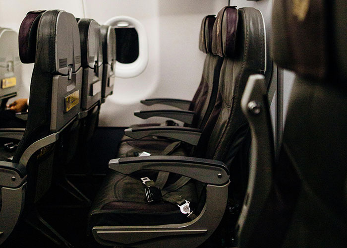 Airplane cabin seats with empty black leather chairs and a window, illustrating entitled person behavior in crowded spaces.
