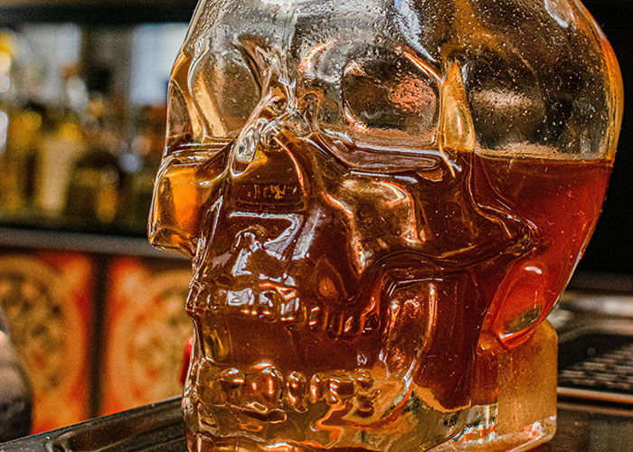 Glass skull-shaped bottle filled with amber liquid, highlighting an unusual and insensitive gift idea related to gym membership.