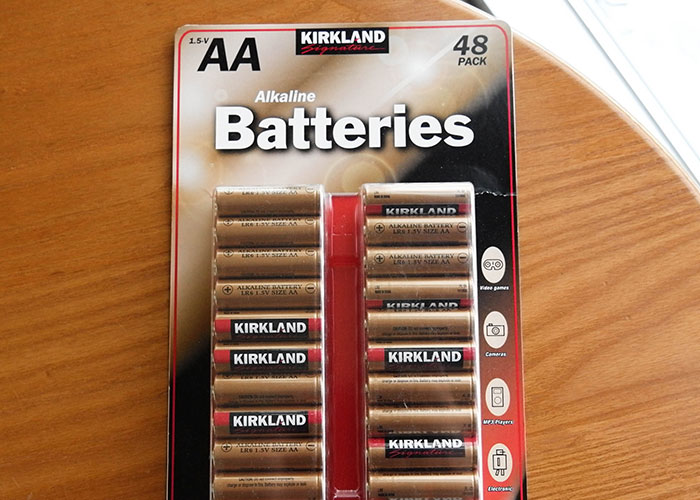 48-pack of AA Kirkland alkaline batteries on a wooden table, an example of insensitive gym membership gifts.