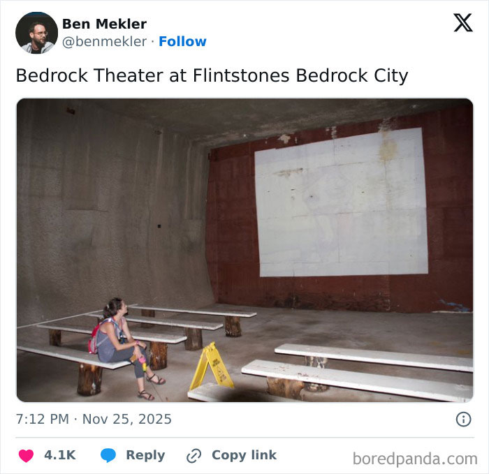 Person sitting alone on wooden benches in a rundown, empty movie theater with a faded screen and concrete walls.