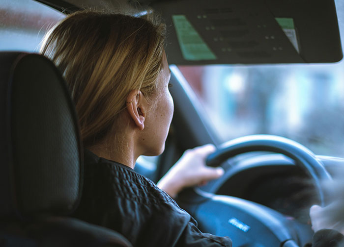 A woman driving a car, shown from behind, reflecting on the worst things patients had to go through in hospitals.