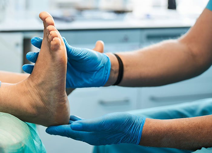 Healthcare worker wearing blue gloves examining a patient's foot, highlighting worst things patients had to go through.