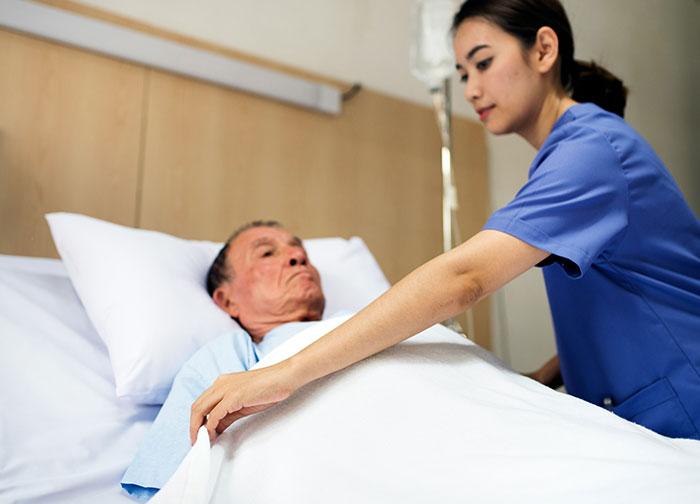 Nurse caring for an elderly patient in hospital bed, illustrating some of the worst experiences patients had to go through.