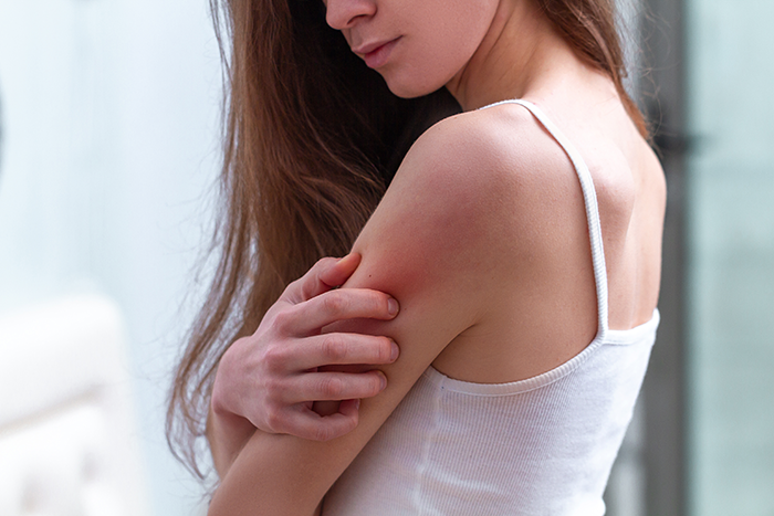 Woman in white tank top touching her arm, showing unexplained scratches, husband with trust issues considering CCTV installation. Woman in white tank top touching her arm, showing unexplained scratches, husband with trust issues considering CCTV installation.