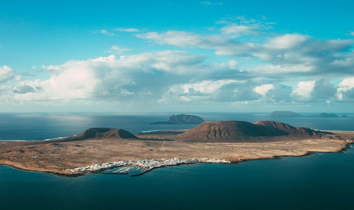 Aerial view of a coastal island with mountains and a small settlement, people share historical facts unknown recently.