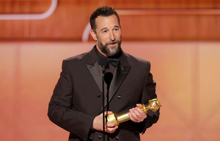 Noah Wyle in a black suit holding an award on stage, related to questions about leaving The Pitt in season 2. Noah Wyle in a black suit holding an award on stage, related to questions about leaving The Pitt in season 2.
