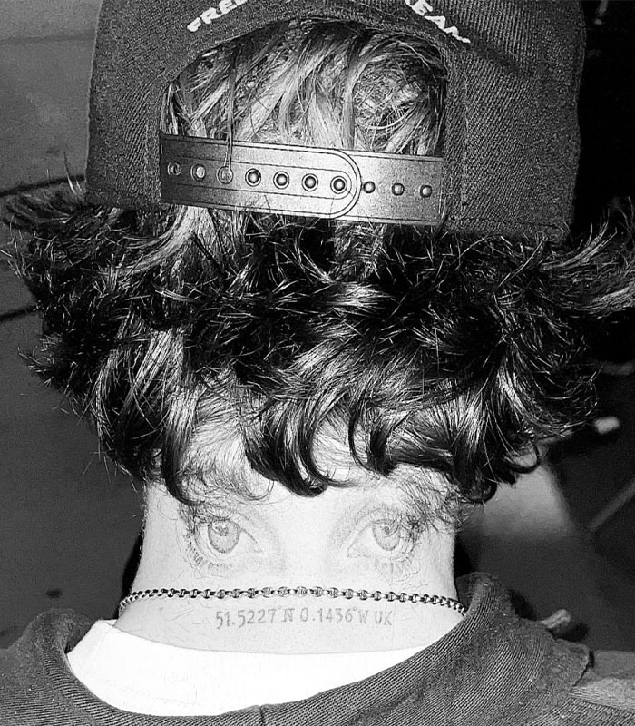 Black and white image showing the back of a person's head with a cap and a tattoo of eyes and coordinates on the neck, sister of Nicola Peltz's ex. Black and white image showing the back of a person's head with a cap and a tattoo of eyes and coordinates on the neck, sister of Nicola Peltz's ex.