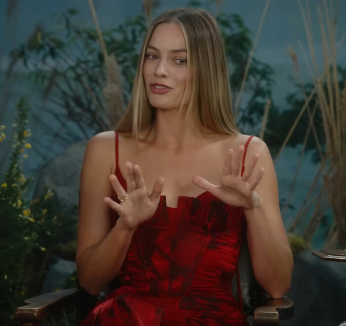 Margot Robbie in a red dress discussing her on-set relationship with Wuthering Heights co-star Jacob Elordi during an interview. Margot Robbie in a red dress discussing her on-set relationship with Wuthering Heights co-star Jacob Elordi during an interview.