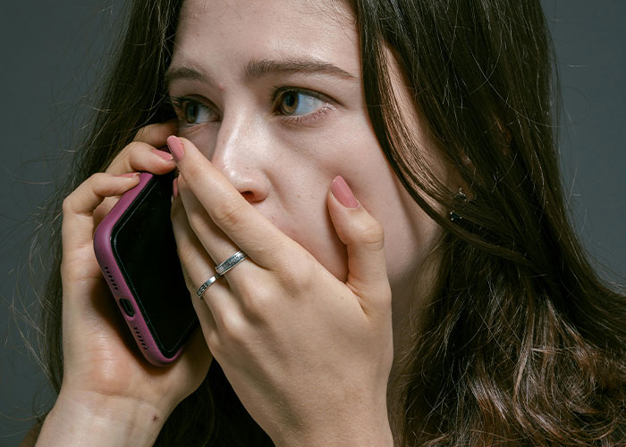 Woman with worried expression holding phone to ear, reacting during a tense moment involving babysitting and a call for help.