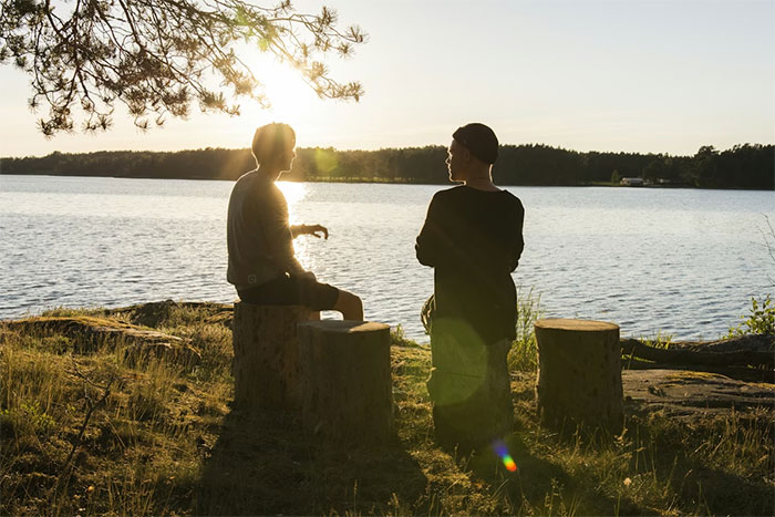 guy embarrasses wife scene: two people silhouetted by a lakeshore at sunset, one gesturing while the other listens guy embarrasses wife scene: two people silhouetted by a lakeshore at sunset, one gesturing while the other listens