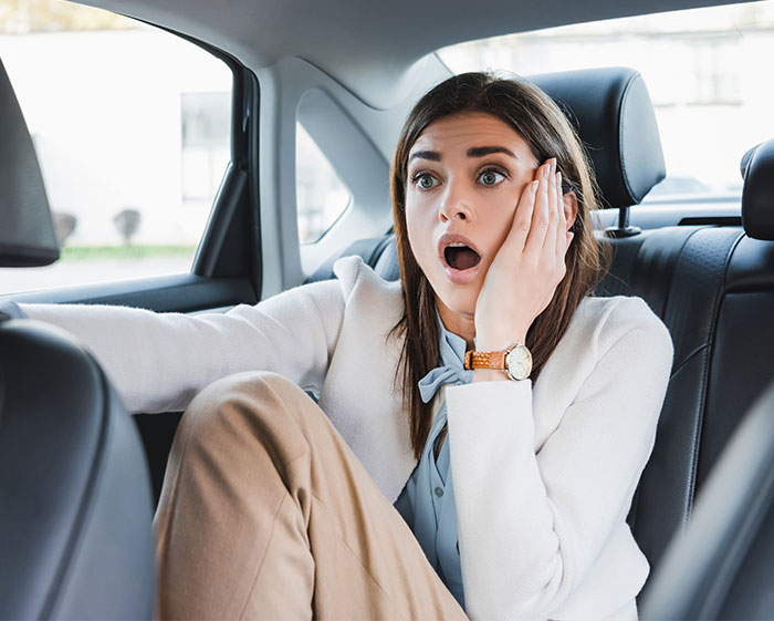 Young woman having an anxiety meltdown in the back seat of a car, illustrating risk and front seat ban. Young woman having an anxiety meltdown in the back seat of a car, illustrating risk and front seat ban.