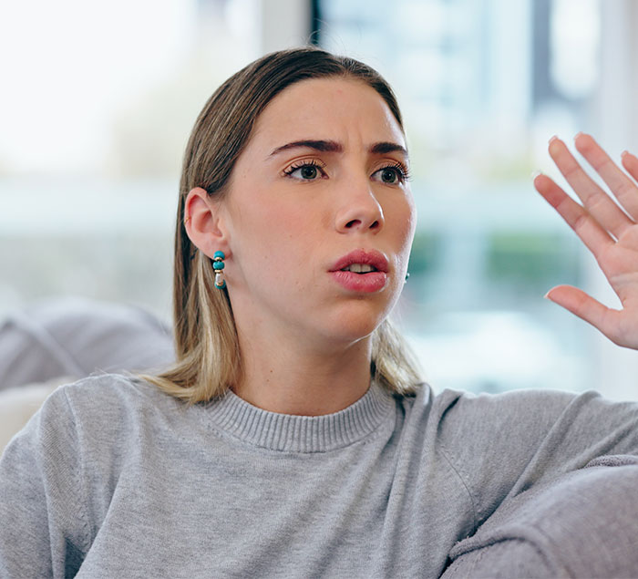 Young woman raising hand, expressing frustration in a tense conversation about manipulative controlling behavior. Young woman raising hand, expressing frustration in a tense conversation about manipulative controlling behavior.
