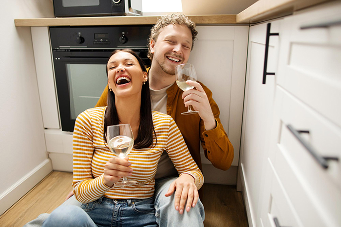 Woman and husband laughing in kitchen holding wine glasses, highlighting family lying snobs with a simple switch. Woman and husband laughing in kitchen holding wine glasses, highlighting family lying snobs with a simple switch.