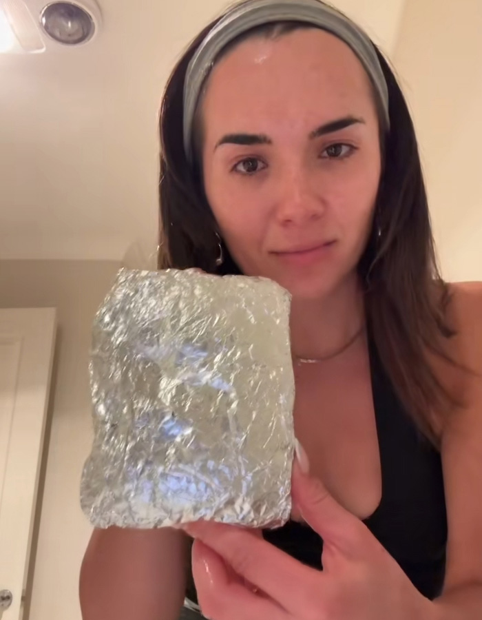 Woman showing a foil-wrapped package brought by Hinge match on their first date, looking stunned and surprised. Woman showing a foil-wrapped package brought by Hinge match on their first date, looking stunned and surprised.