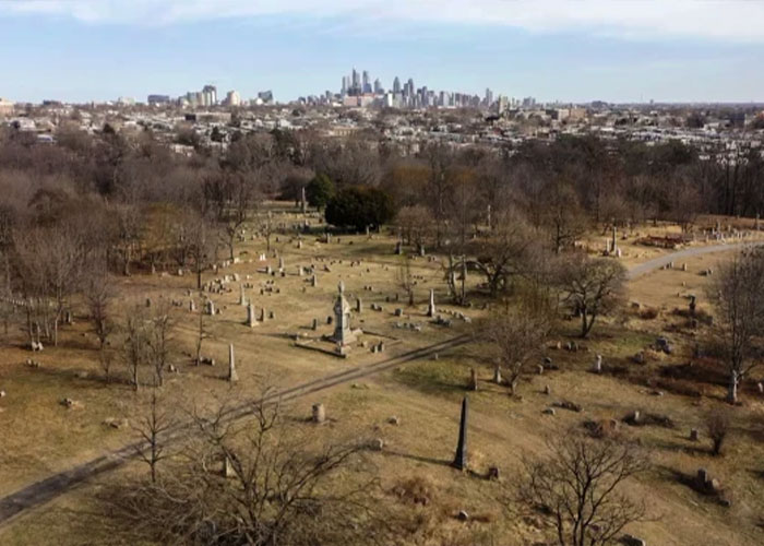 Aerial view of a chilling house near a city skyline with barren trees and old gravestones, hinting at a horrifying discovery.
