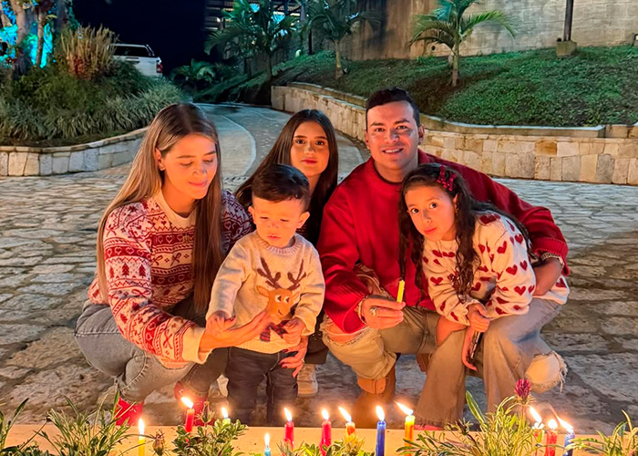 Family gathered outdoors at night, wearing festive sweaters, lighting candles in a heartfelt moment for famous singer. Family gathered outdoors at night, wearing festive sweaters, lighting candles in a heartfelt moment for famous singer.