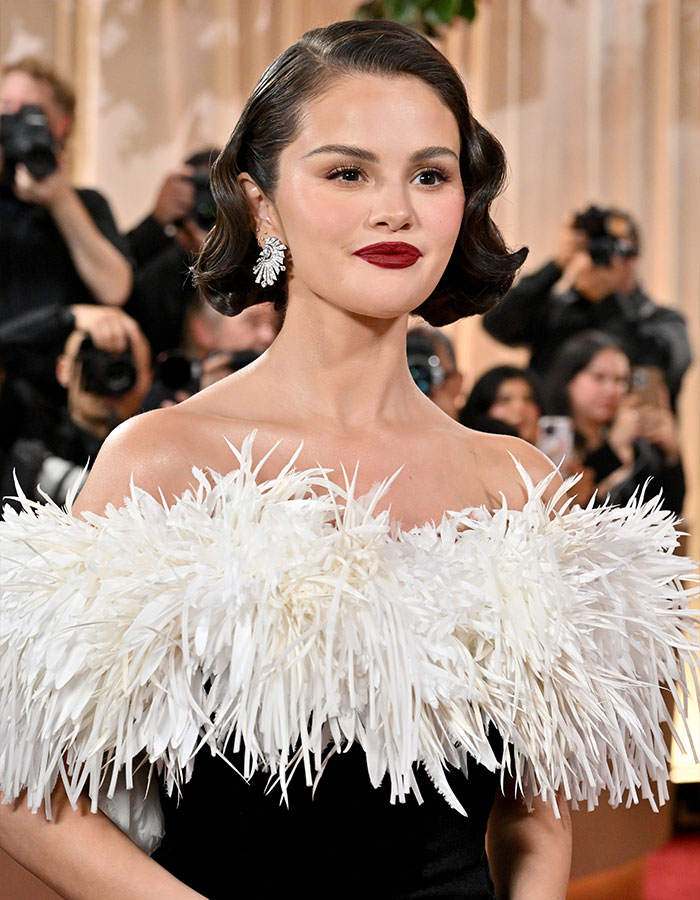 Selena Gomez wearing a feathered dress and bold red lipstick at the Golden Globes amid plagiarism accusations