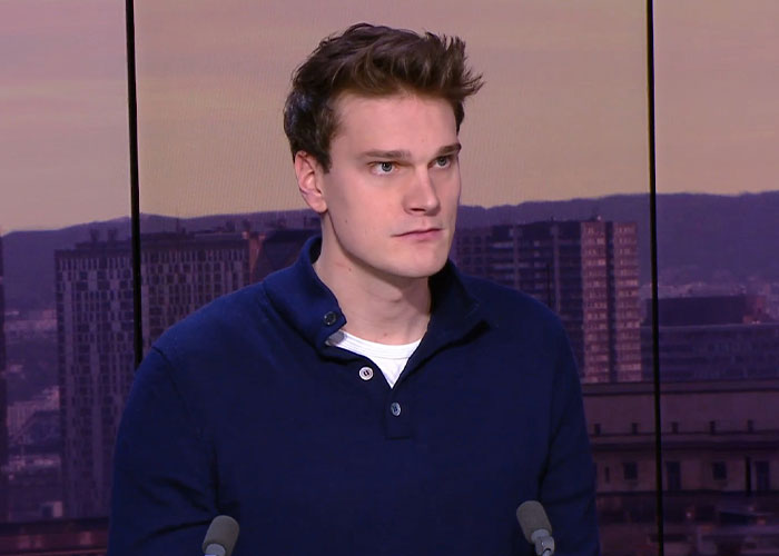 Young man in dark blue shirt speaking seriously in a news studio, related to Olympic gold medalist crime case.