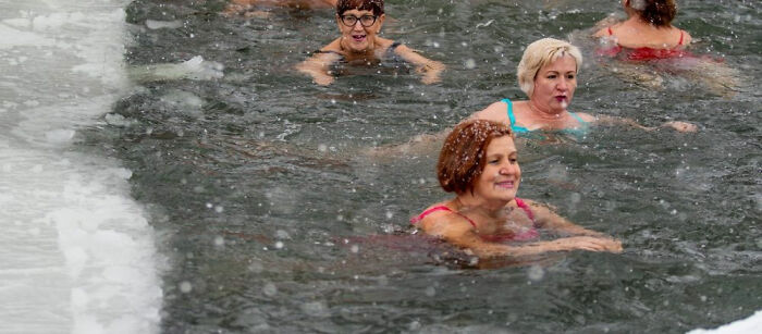 Four women swimming in icy water surrounded by snow, illustrating strange traditions from around the world.