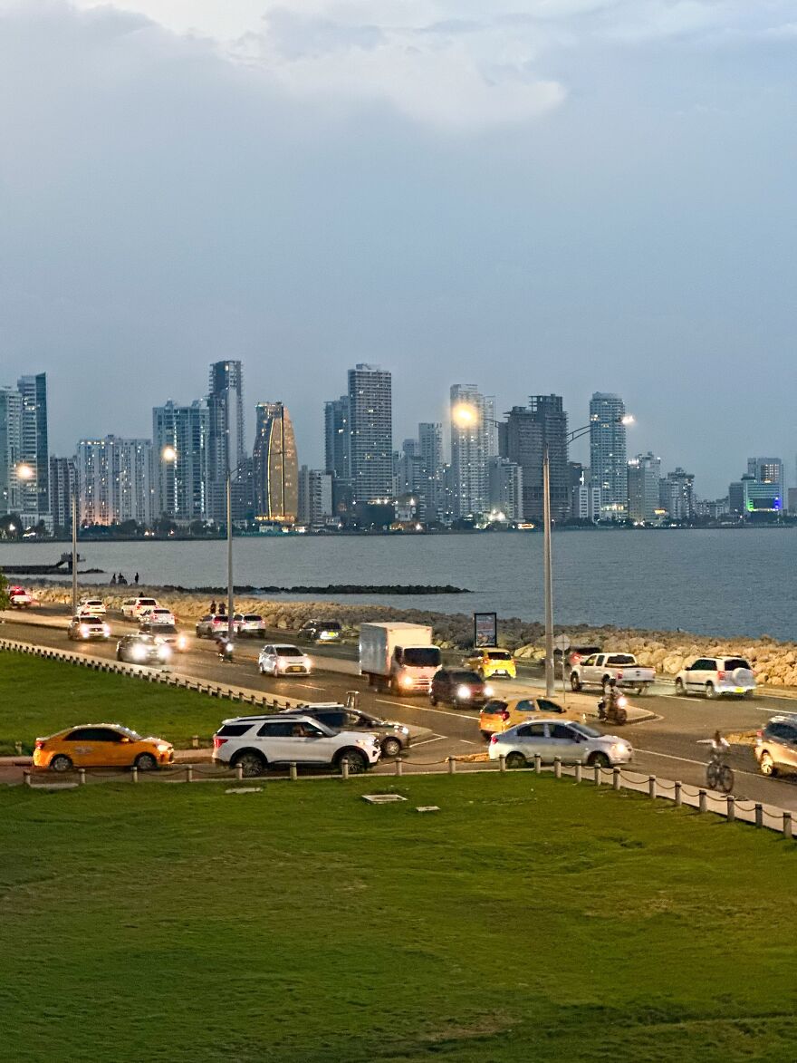 Traffic congestion at dusk on a coastal road with city skyline in the background in cities with worst traffic.