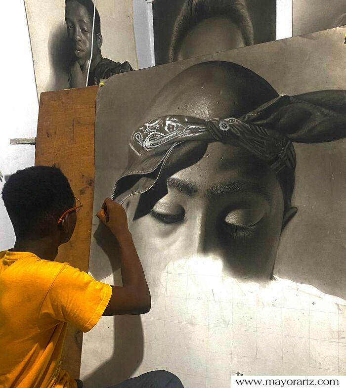 Artist creating a hyperrealistic portrait of a person wearing a bandana, showing detailed shading and facial features.