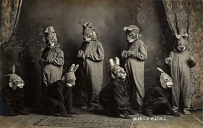 Group of people wearing old black and white creepy animal masks and costumes in a vintage eerie setting