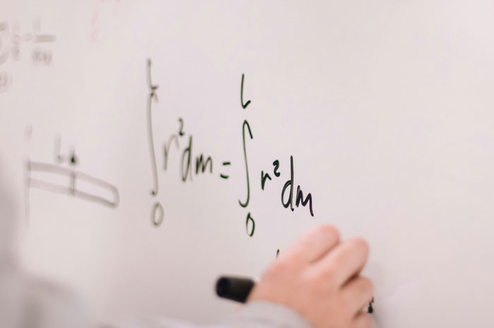 Person writing complex mathematical equations on a whiteboard demonstrating borderline creepy smart thinking skills