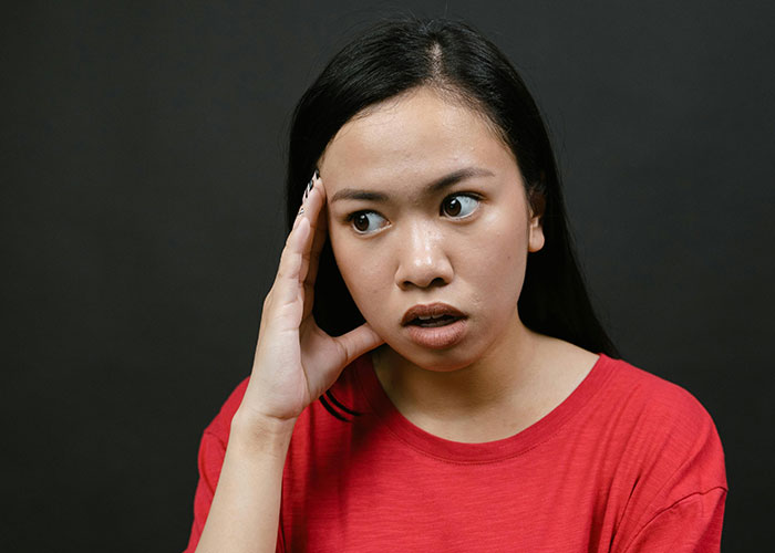 Young woman in red shirt looking surprised and thoughtful, illustrating kids with no filter revealing family lore.