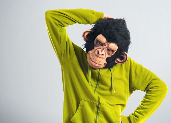 Person wearing a monkey mask and green hoodie striking a quirky pose showcasing weird things people did in public.