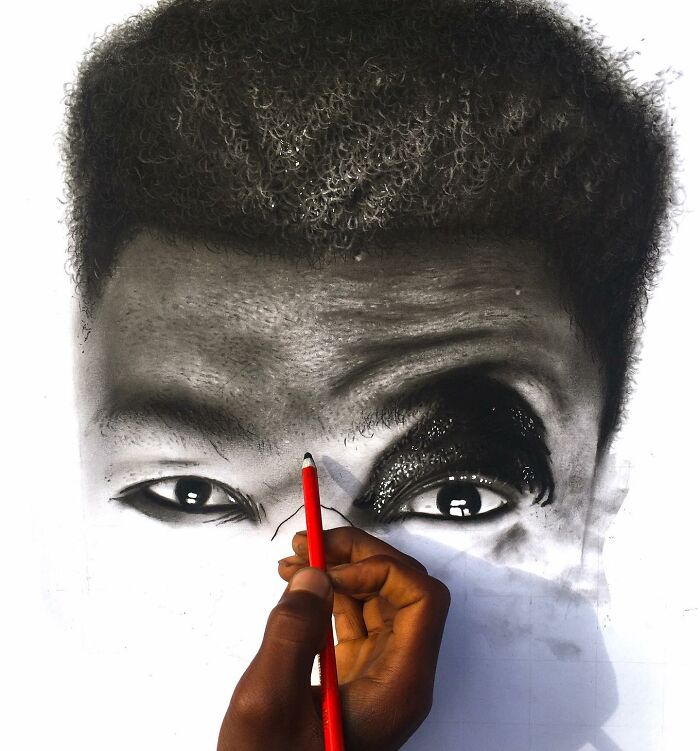 Hand drawing a hyperrealistic portrait with a red pencil, capturing detailed eyes and hair texture in black and white.
