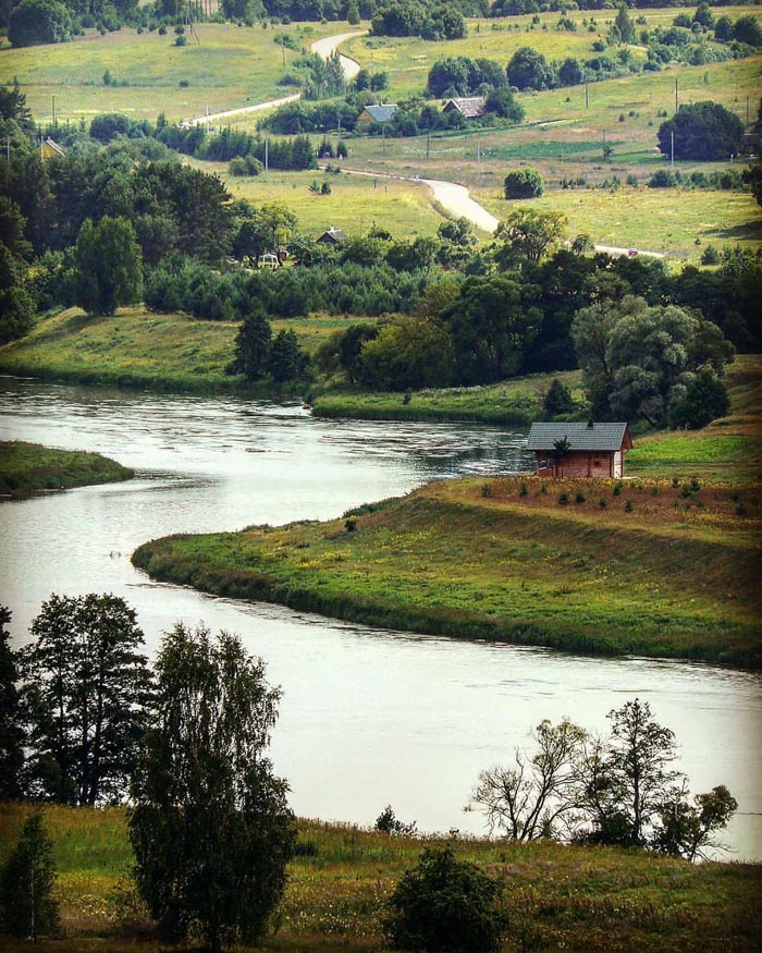 Scenic countryside with river and greenery representing countries that sleep the most based on OECD time use data.
