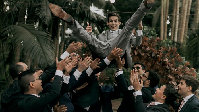 Group of men in suits lifting a man in a grey suit, casting a vote on whether they did the right thing.
