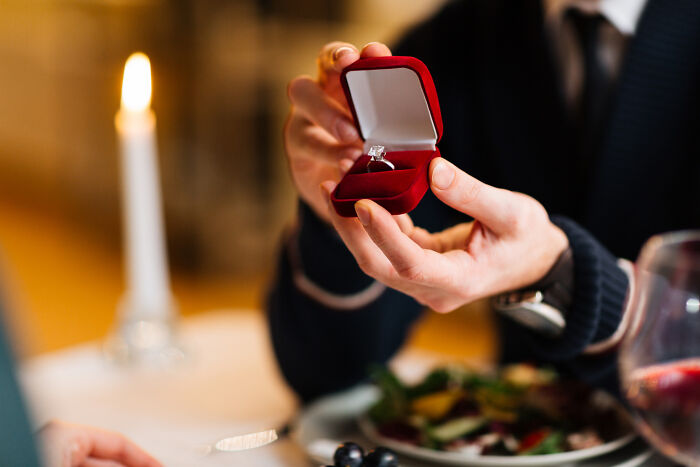Person holding a ring box in a restaurant setting, capturing an awkward moment in the service industry.