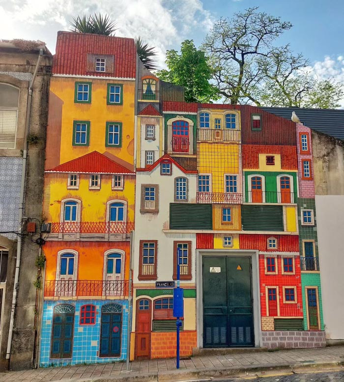 Colorful street mural of buildings in a city illustrating countries that sleep the most based on OECD time use data.