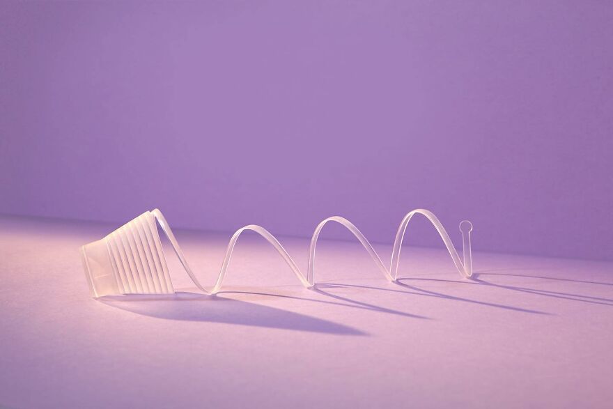 Flexible transparent spiral tube designed with biomimicry principles on a purple surface with soft shadows.