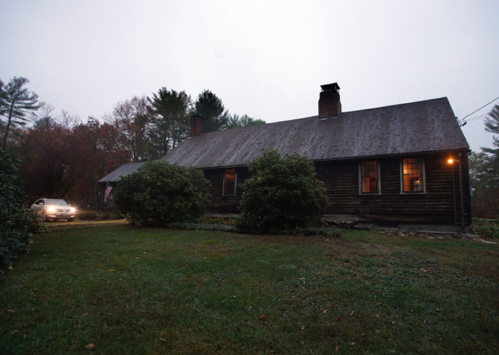 Old dark house at dusk with lit windows and a car approaching, representing haunted places in America. Old dark house at dusk with lit windows and a car approaching, representing haunted places in America.