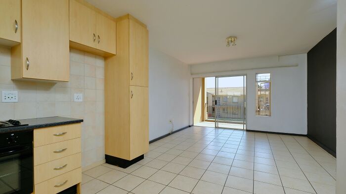 Empty modern apartment with tiled floor and wooden kitchen cabinets, inviting you to decide if they did the right thing.
