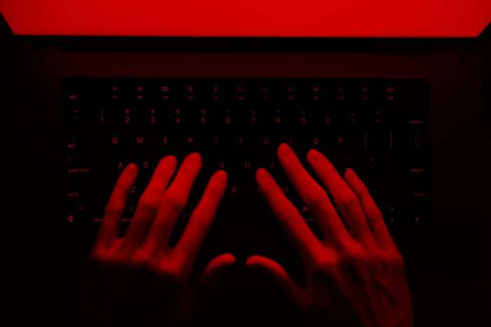 Hands typing on a keyboard under red light, showing smart and borderline creepy focused computer work.
