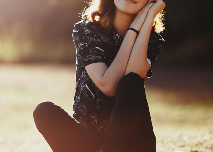 Young woman sitting outdoors in sunlight, reflecting on habits neurodivergent people thought were normal.