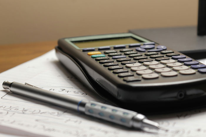 Scientific calculator and pen on paper with mathematical notes, illustrating moments of smart thinking and clever problem solving.