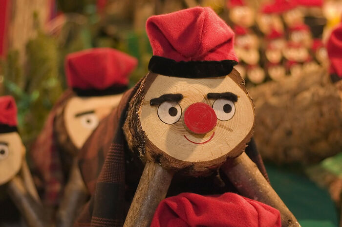 Wooden log figures with red hats, part of strange and unique traditions from around the world.