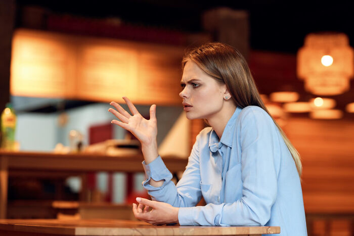 Young woman in service industry uniform looking frustrated and confused during an awkward moment at work.