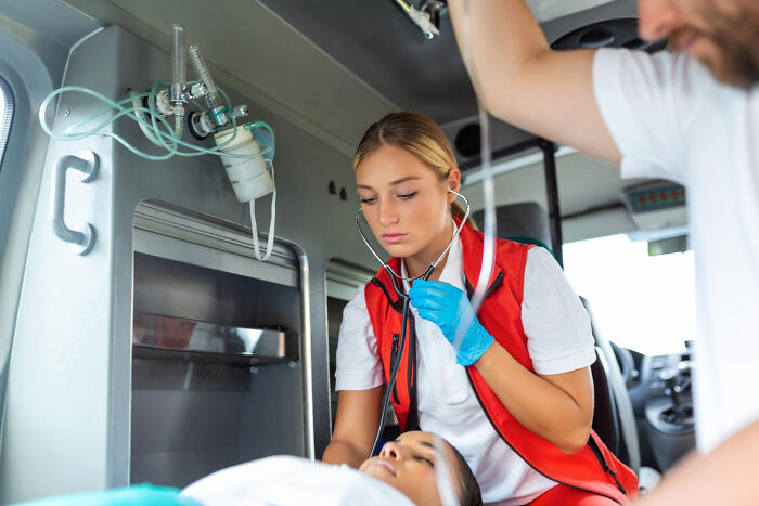 Paramedic in a red vest using a stethoscope to check a patient inside an ambulance during a moment so ridiculous it seemed like a prank