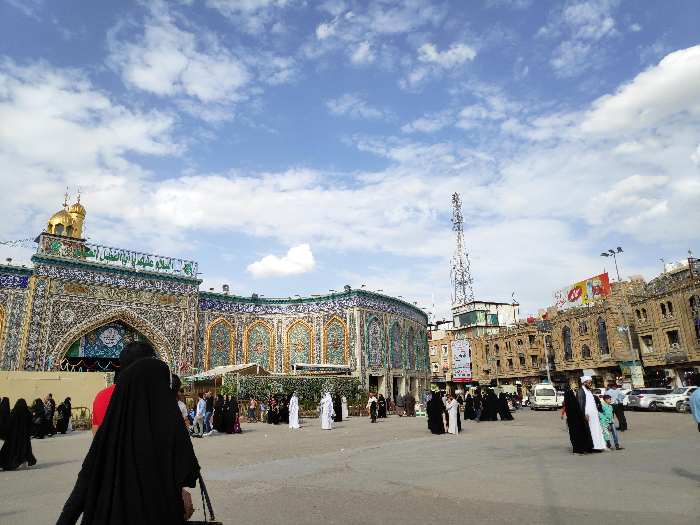 Crowd near ornate tiled shrine with golden dome and blue sky, visual for most stressful countries