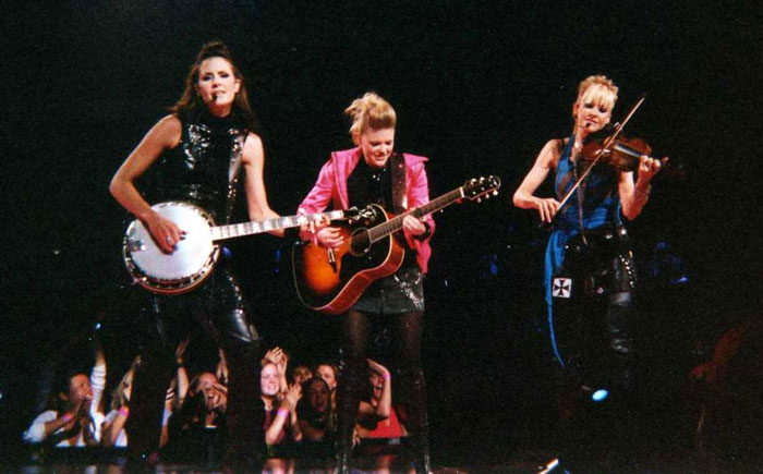 Three female musicians performing on stage with banjo, guitar, and violin as part of celebrities whose careers crashed and never recovered.