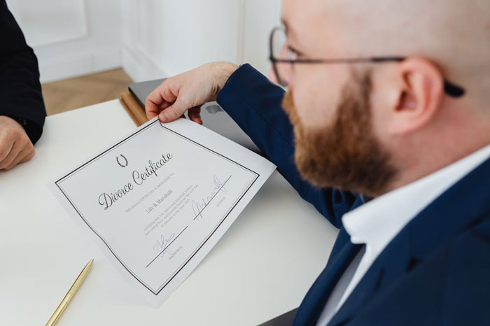 Man in glasses and suit holding a divorce certificate during a discussion, illustrating complex family dynamics with multiple parents. Man in glasses and suit holding a divorce certificate during a discussion, illustrating complex family dynamics with multiple parents.