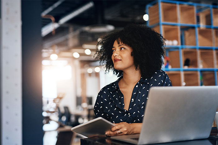 Woman in modern office holding tablet near laptop, focused on coworker filming to prove disability claim.