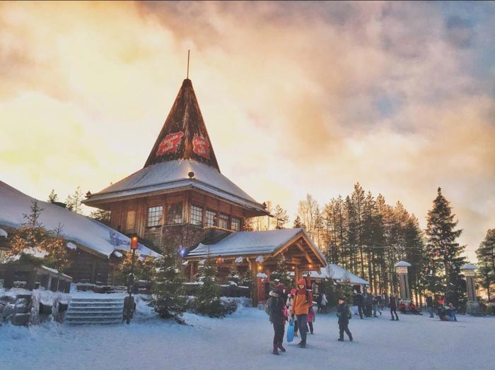 Snow-covered cabin with people outside in winter landscape, illustrating countries that sleep the most in OECD data.